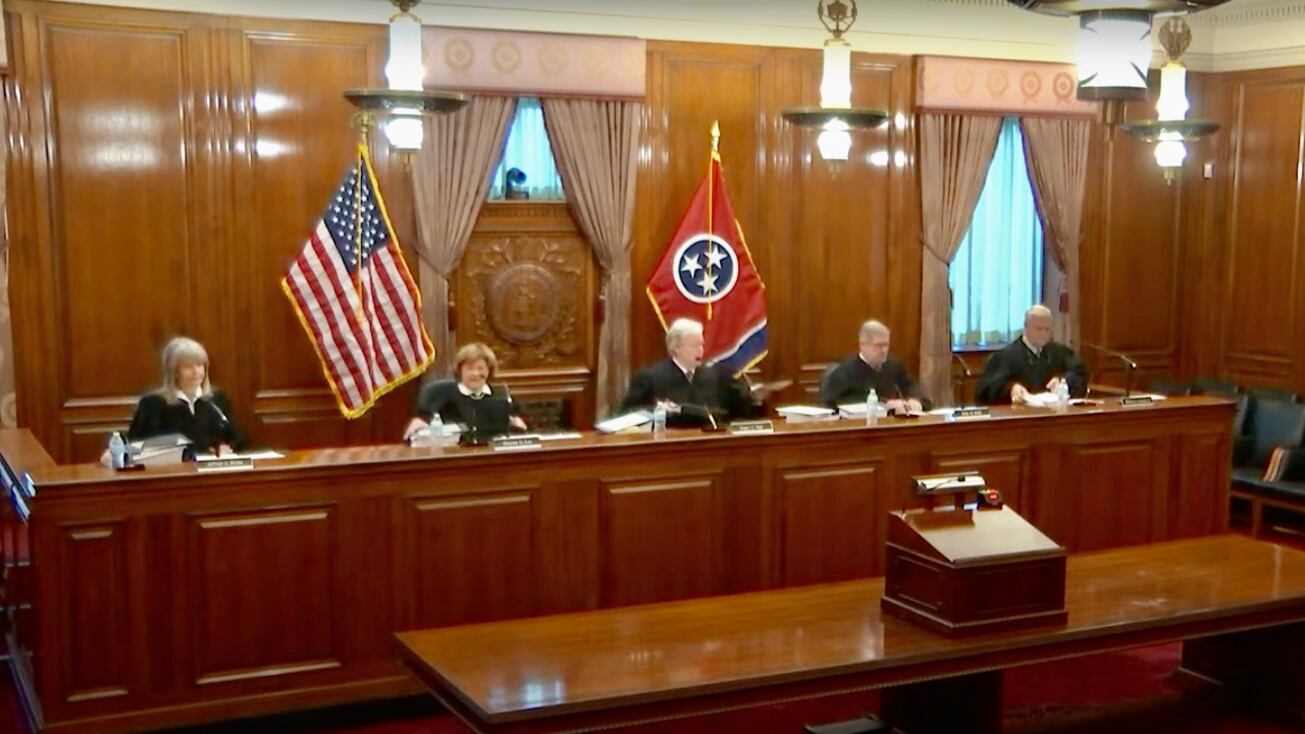 Five judges in black robes sit in a paneled courtroom.