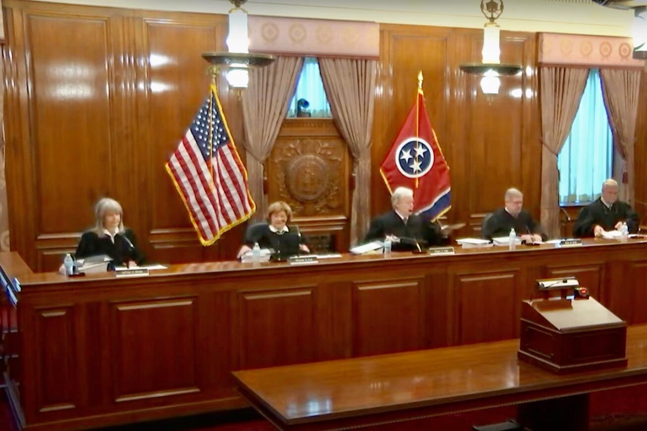 Five judges in black robes sit in a paneled courtroom.