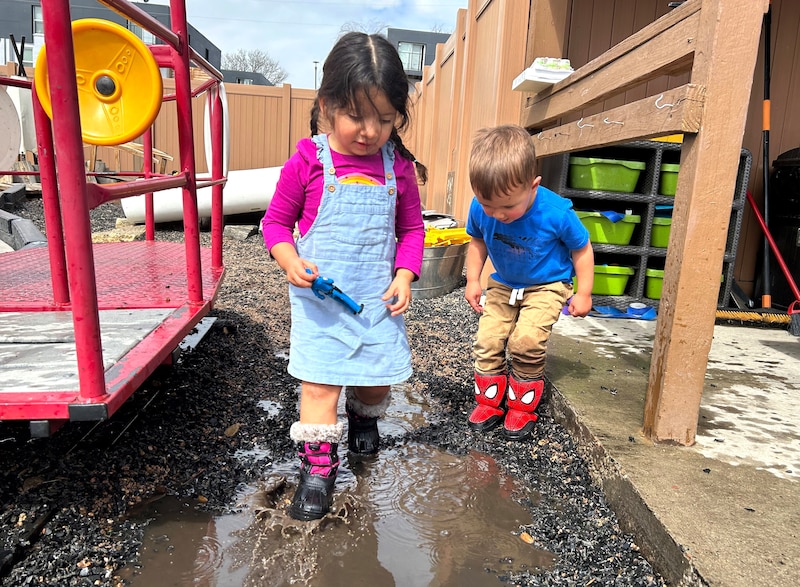 Two children play in mud.