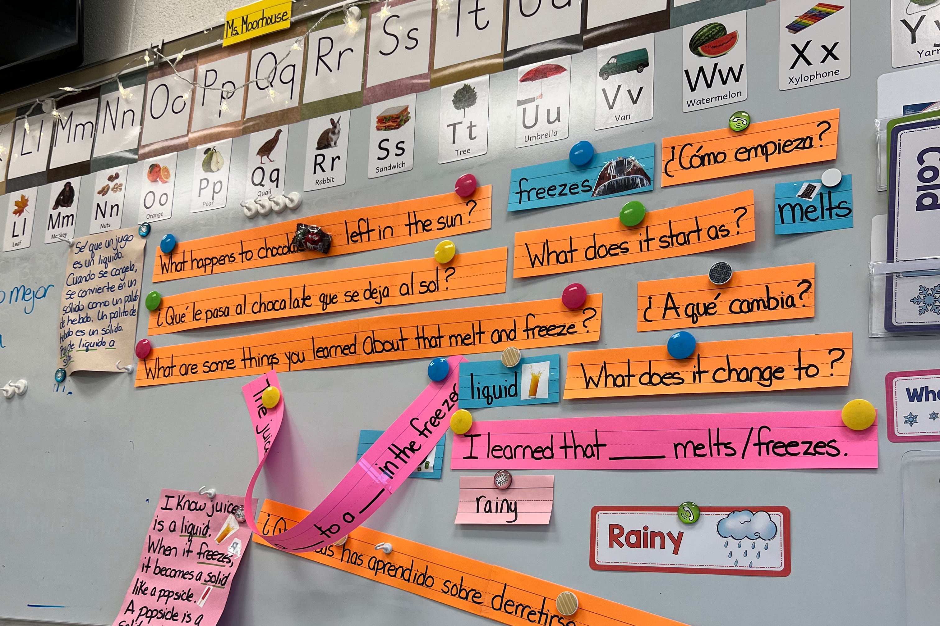 Una pizarra blanca en un aula con textos en español e inglés publicados en ella.