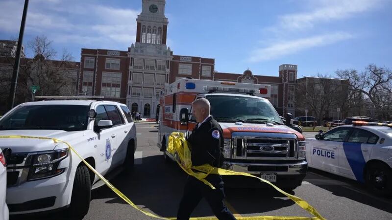 Police cars and ambulances are parked close together in front of Denver’s East High School.