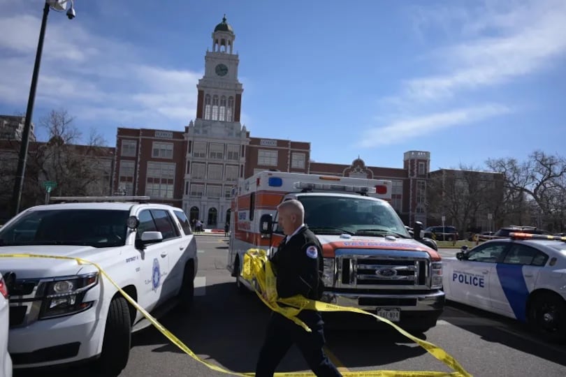 Police cars and ambulances are parked close together in front of Denver’s East High School.