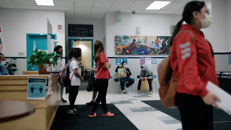 Students walk through the lobby of P.S. 89, with ornate murals on the walls and light blue doors.