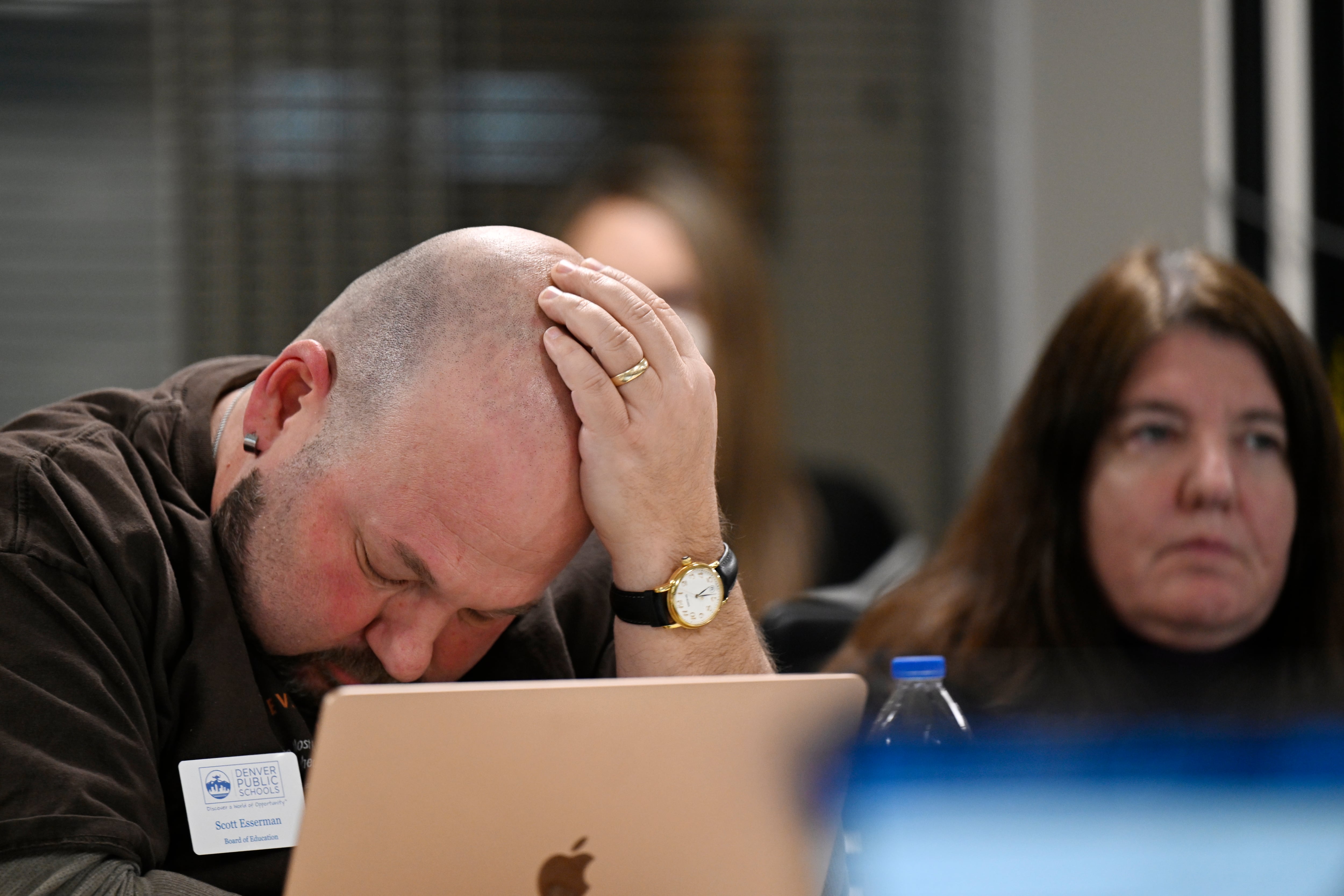 A man holds his head in dismay during a meeting.