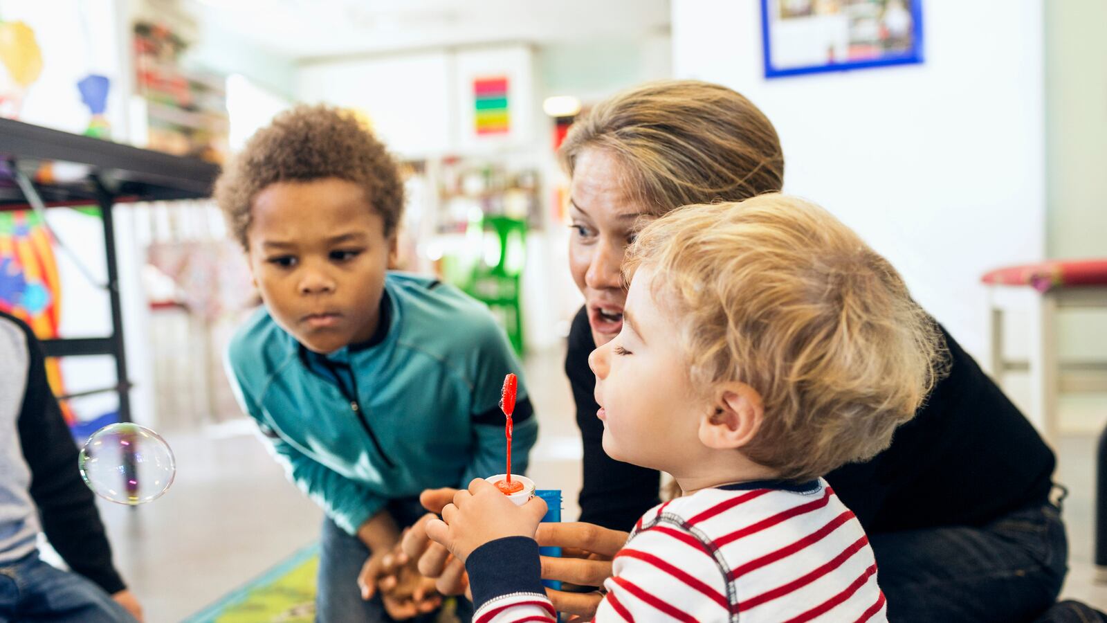 Teacher and children playing with bubbles.