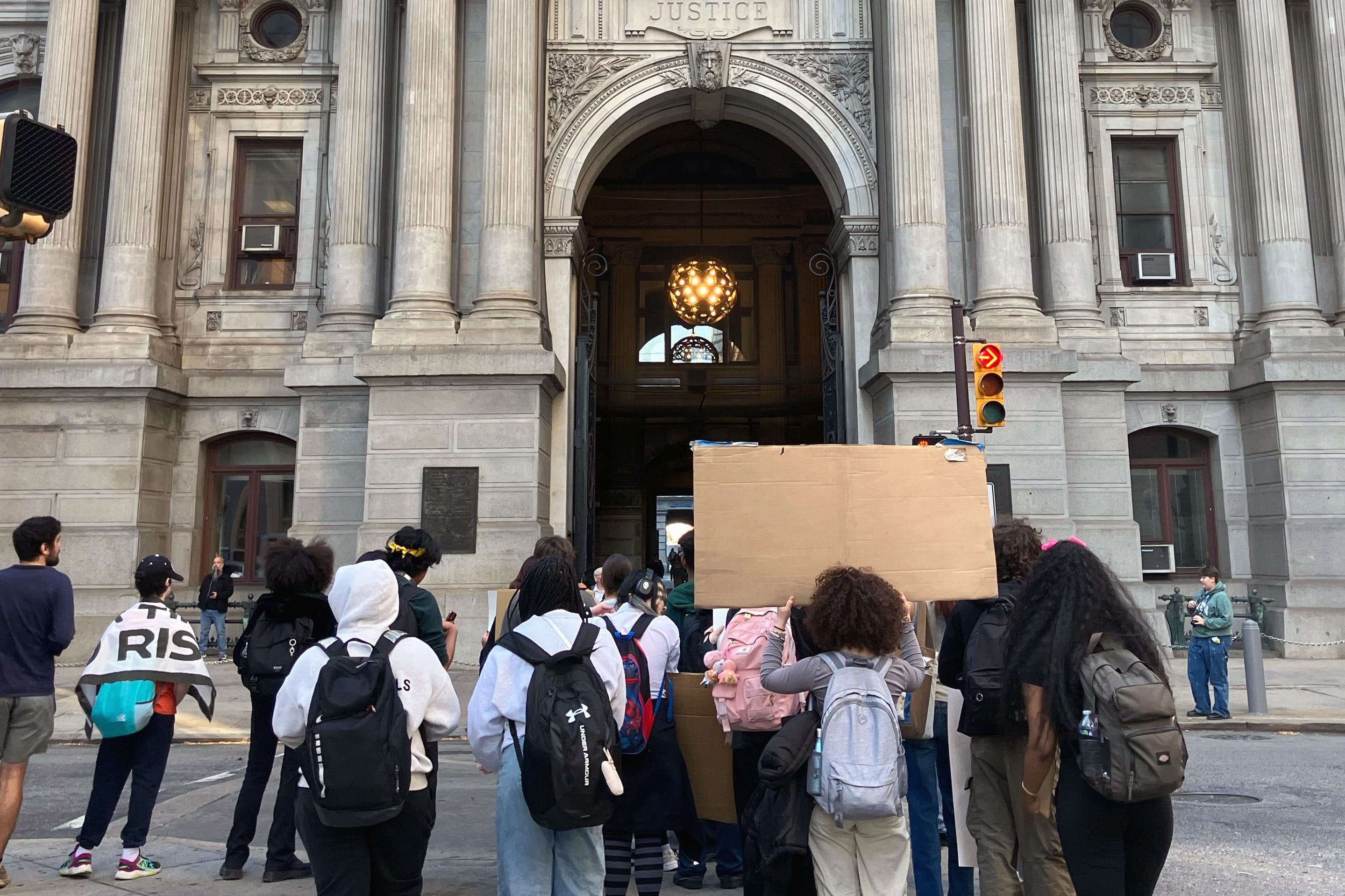 A group of students holding signs walk down the street.