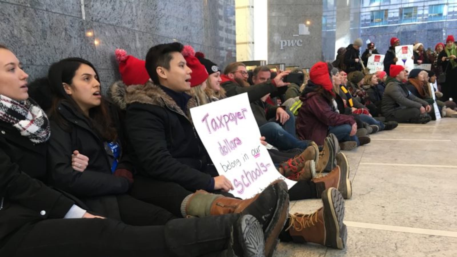 Striking educators from four Chicago International Charter School campuses on Feb. 13, 2019, block a bank of elevators at Pwc, where the charter network's president, Laura Thonn, works.