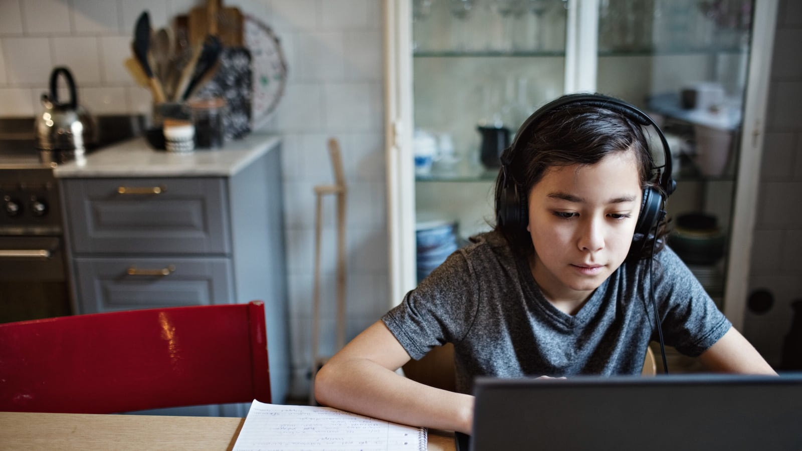 Boy wearing headphones while using laptop during homework at home.
