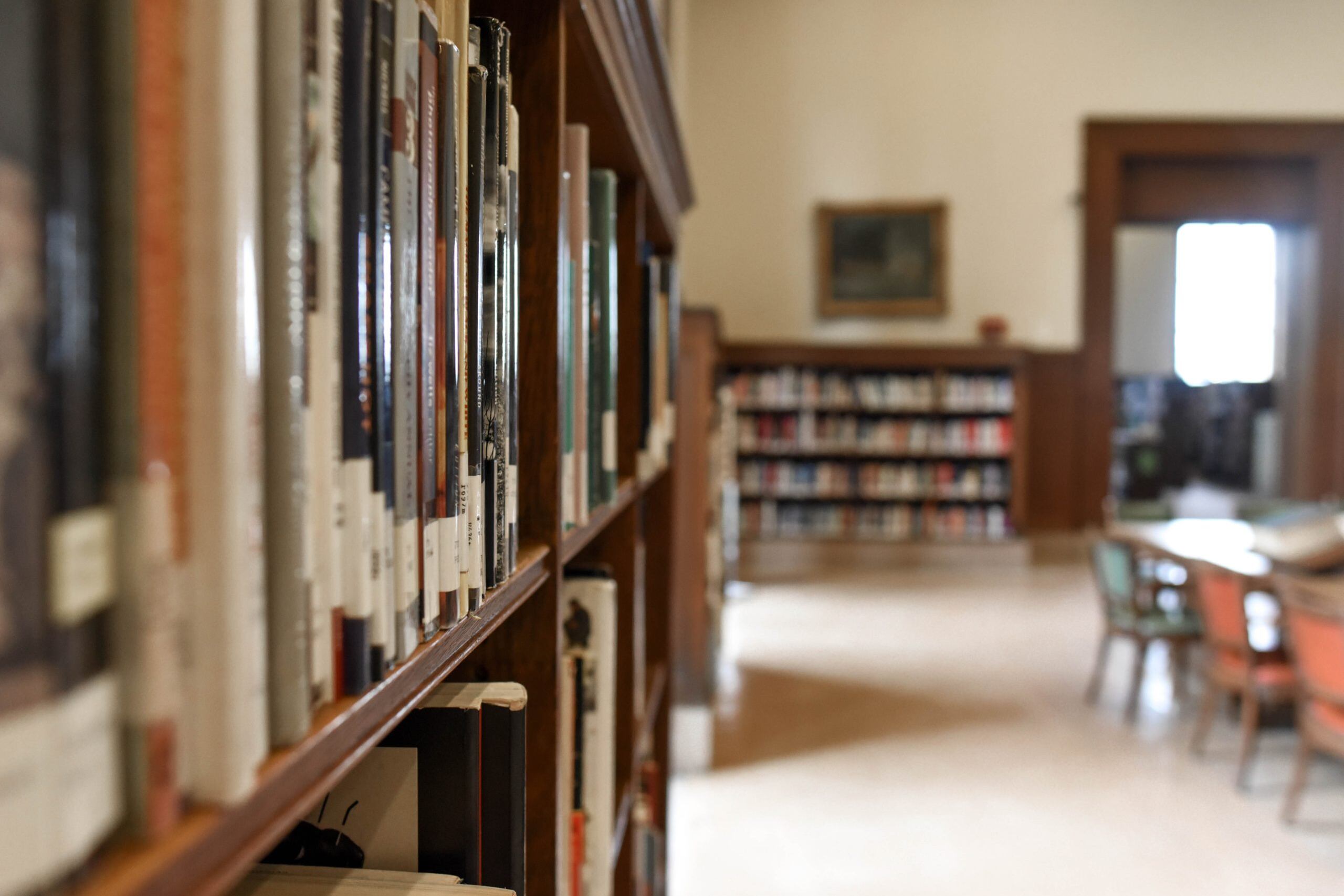 Shallow focus image of a shelf of books in an empty library.