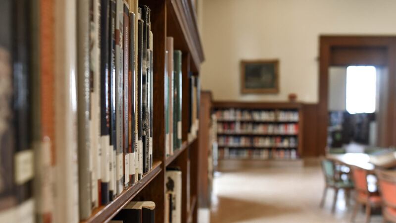 Shallow focus image of a shelf of books in an empty library.