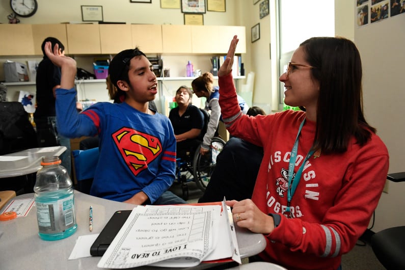 Josue Bonilla, 13, left, gets a high five from his teacher Wendi Sussman, right, after completing a hard reading lesson in his multi-intensive special education class at STRIVE Prep charter school in Denver in 2016.