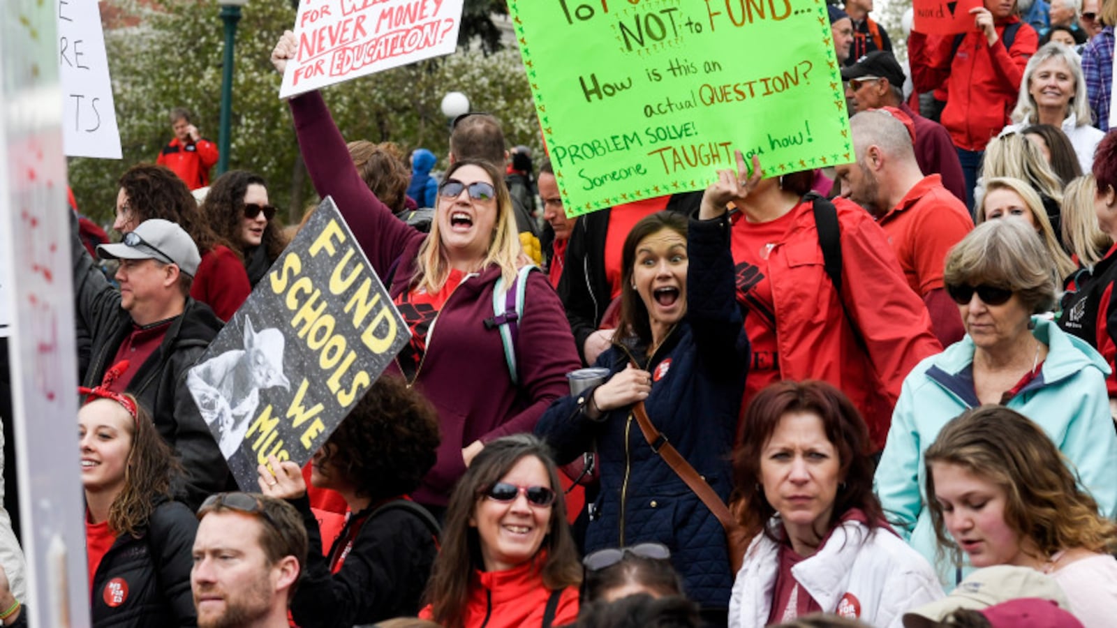 Educators wearing red and holding signs rally for more education funding at the Colorado Capitol on April 26, 2018.