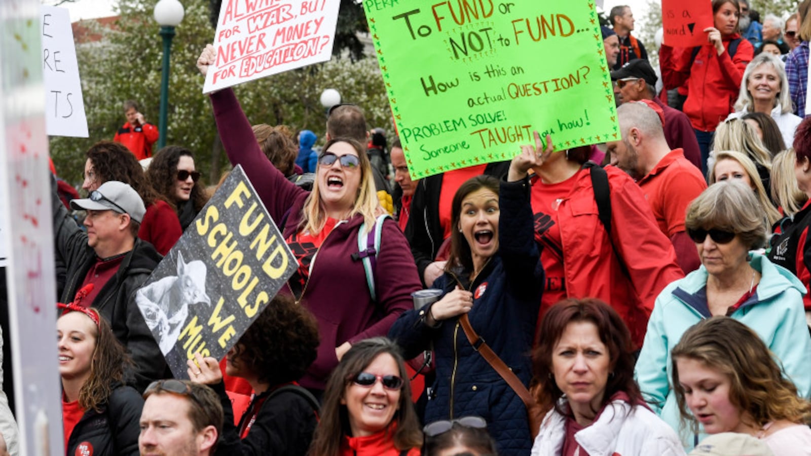 Educators wearing red and holding signs rally for more education funding at the Colorado Capitol on April 26, 2018.