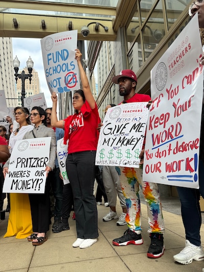 A photograph of a group of people holding large signs outside during a rally.
