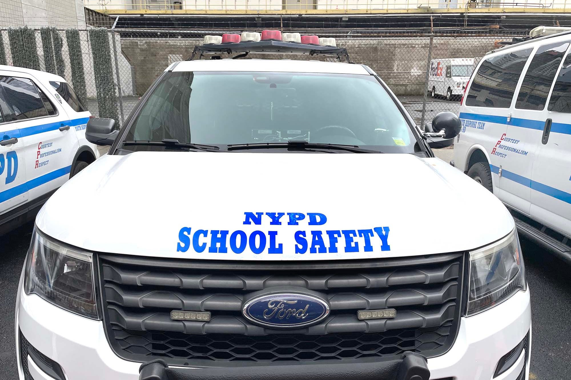 A photograph of three NYPD School Safety vehicles parked outside.