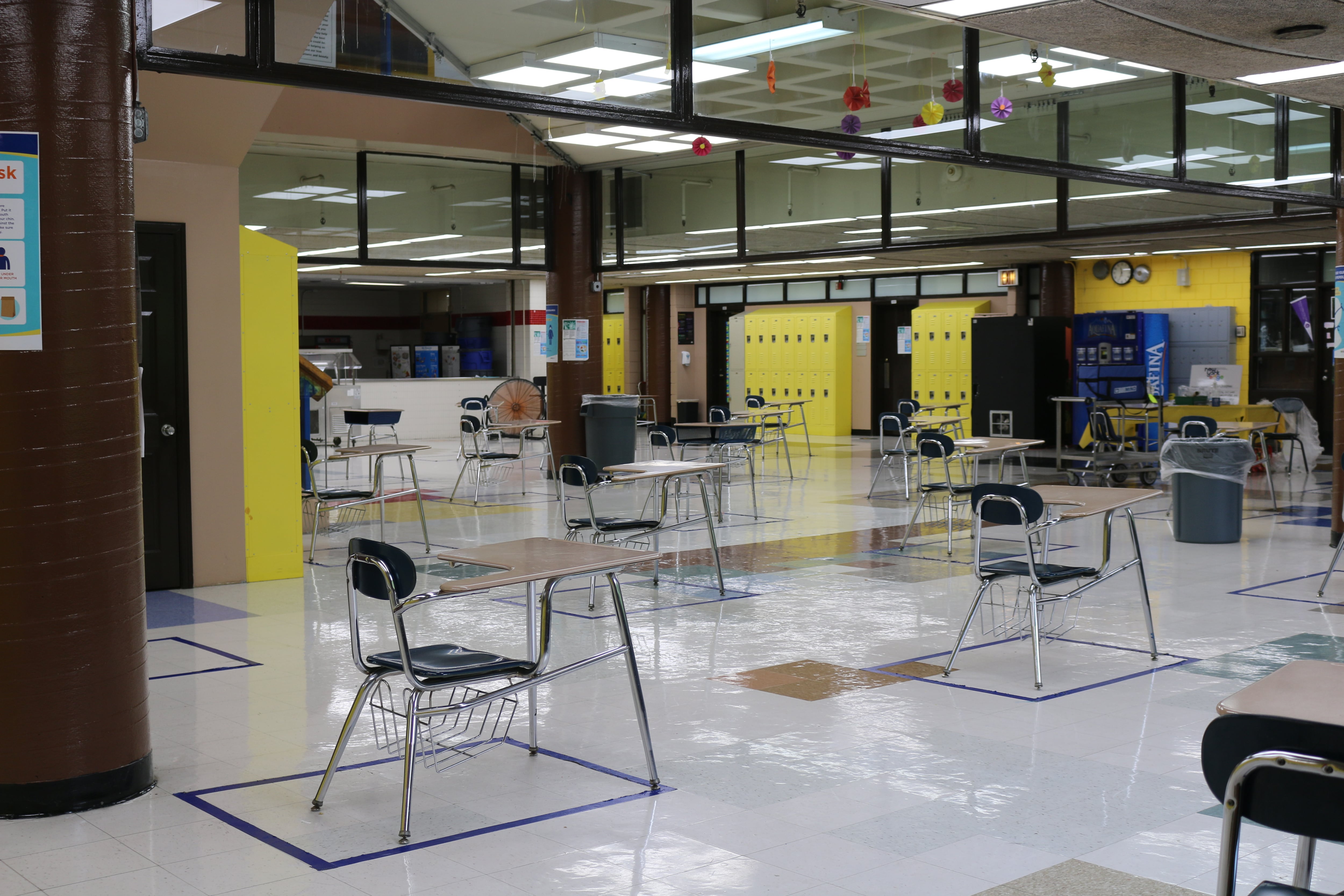 Desks for lunch are socially distanced in a school cafeteria.