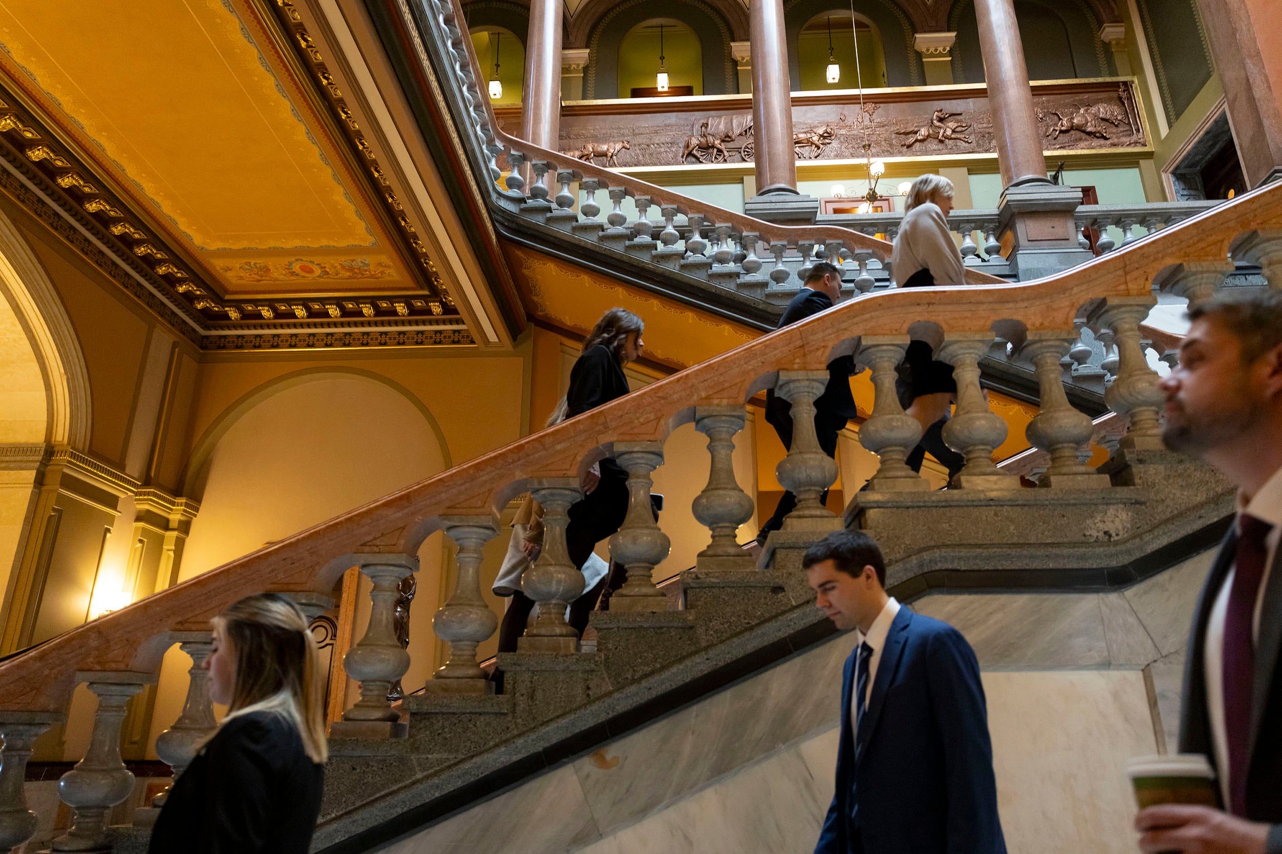 People walk up the stairs in a large capitol building.