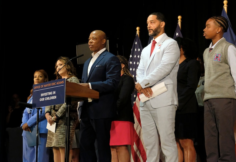 A photograph of a line of adults and one student on stage.