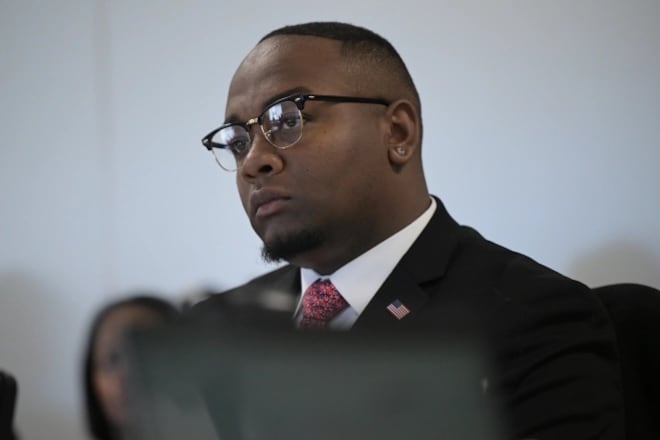 Denver school board Vice President Auon’tai Anderson inside Denver Public Schools headquarters. He is wearing glasses and a suit with a pink tie.