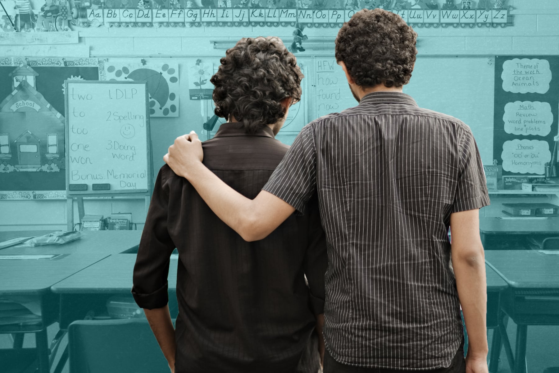 Two teachers, one with his arm around the other’s shoulder consoling him.