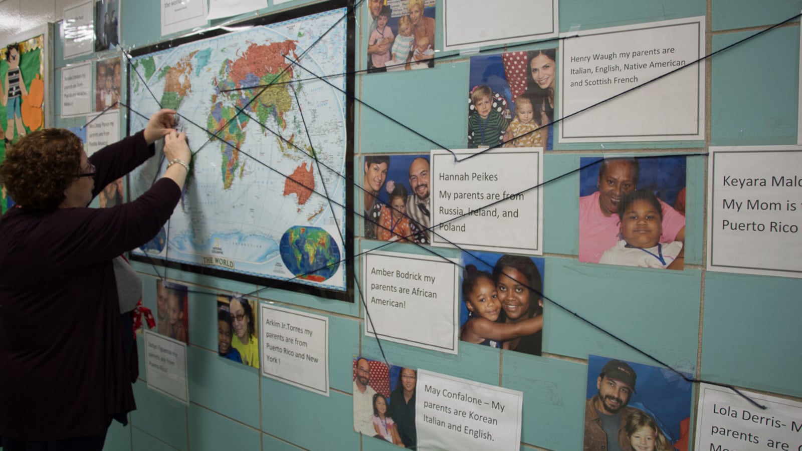 P.S. 15 teacher Giselle Ruiz stands in front of a bulletin board that shows the ethnicities of her students' families.