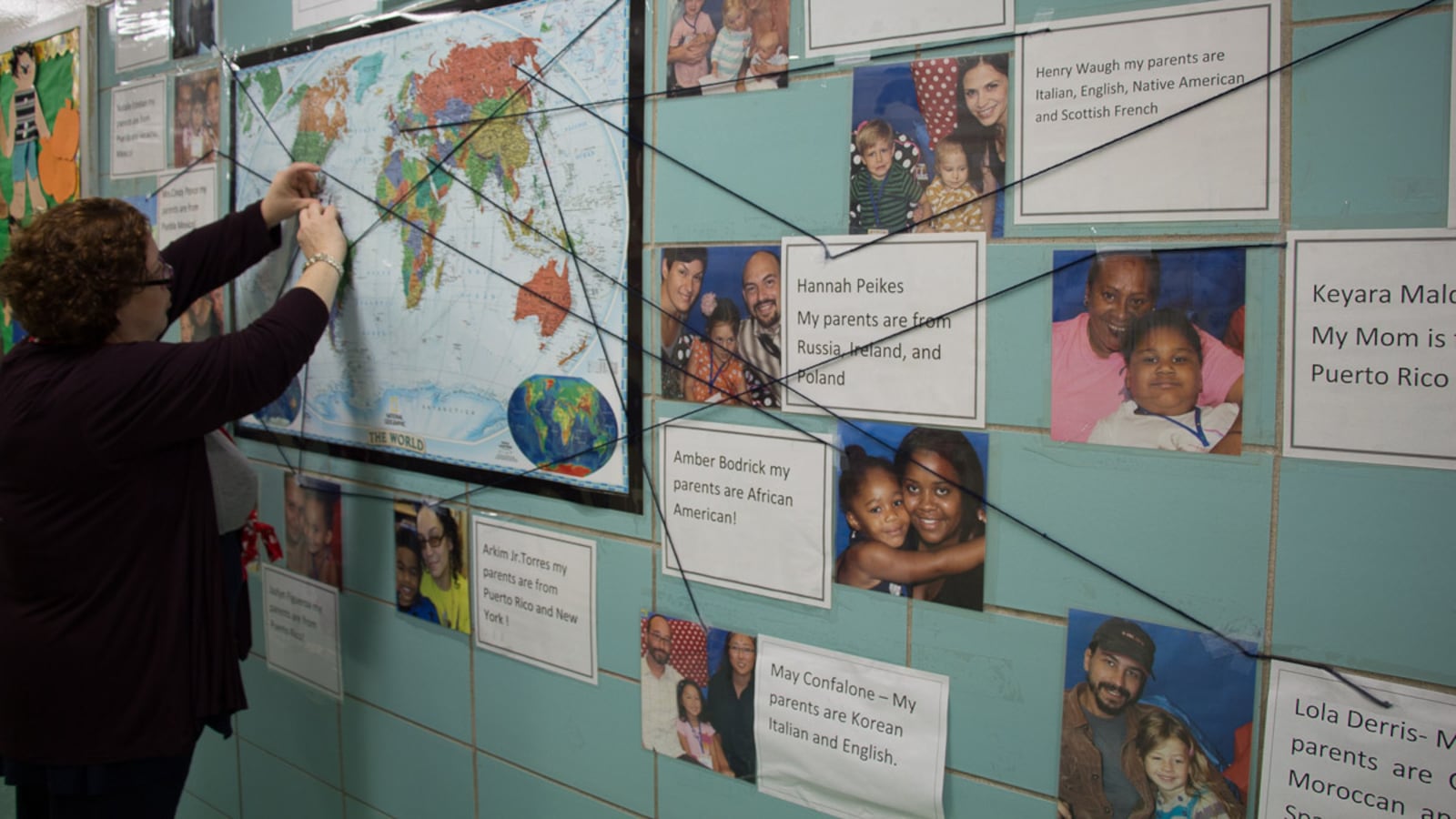 P.S. 15 teacher Giselle Ruiz stands in front of a bulletin board that shows the ethnicities of her students' families.