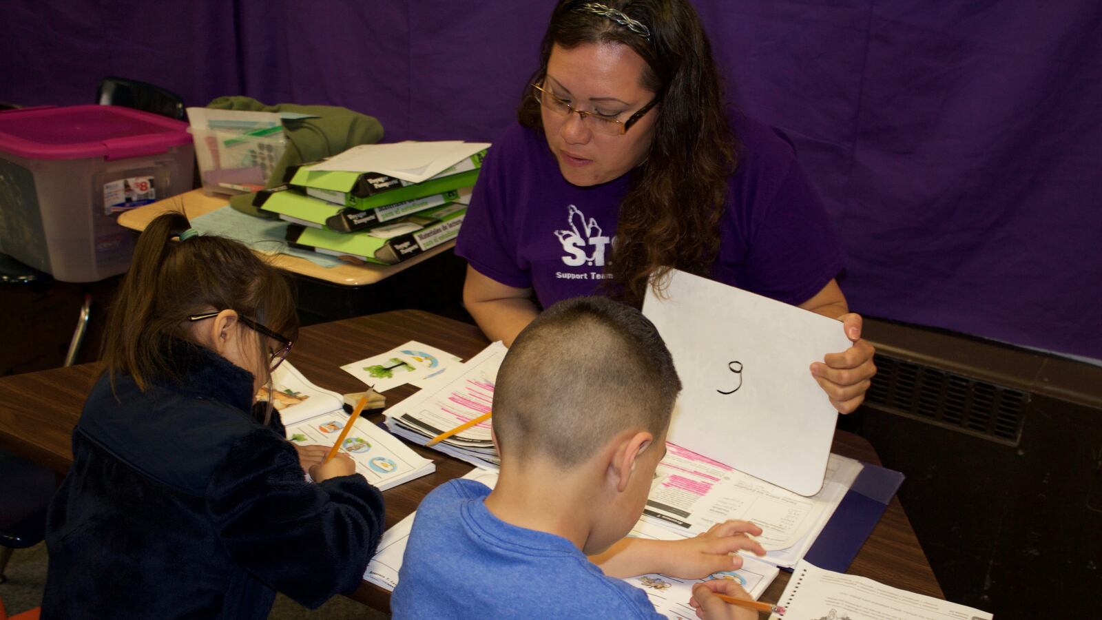 A parent volunteer works with two kindergarteners on reading as part of a pilot program at Dupont Elementary School in Adams County that is training parents to become paraprofessionals.