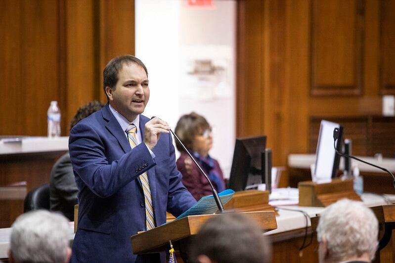 man in suit stands at microphone