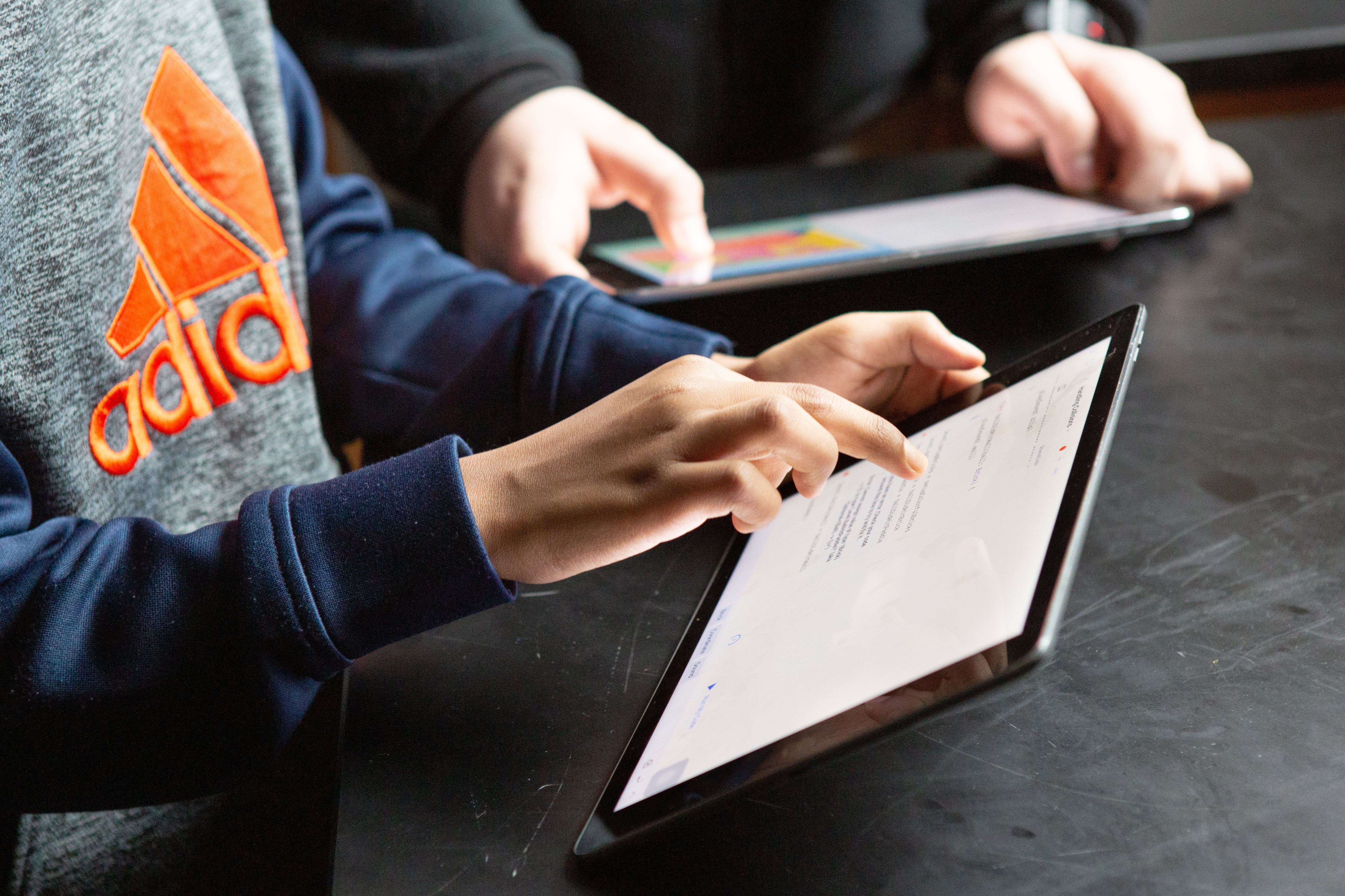 Close up of two young students holding tablets.