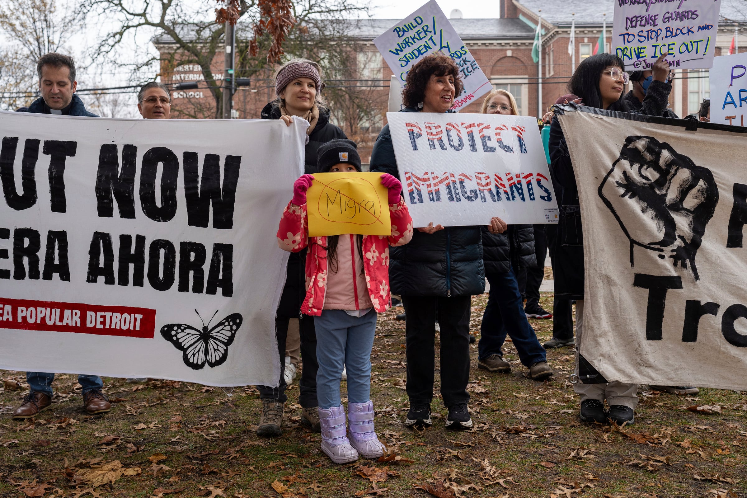 A group of people, including a small child, stand with signs of protest.