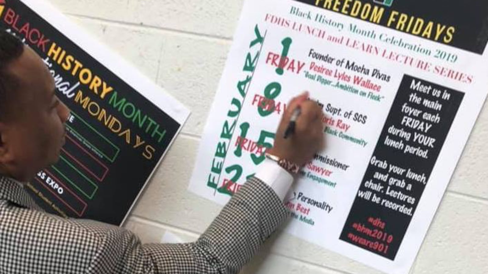 Interim superintendent Joris Ray scratches out "interim" on a flier at Douglass High School in February.