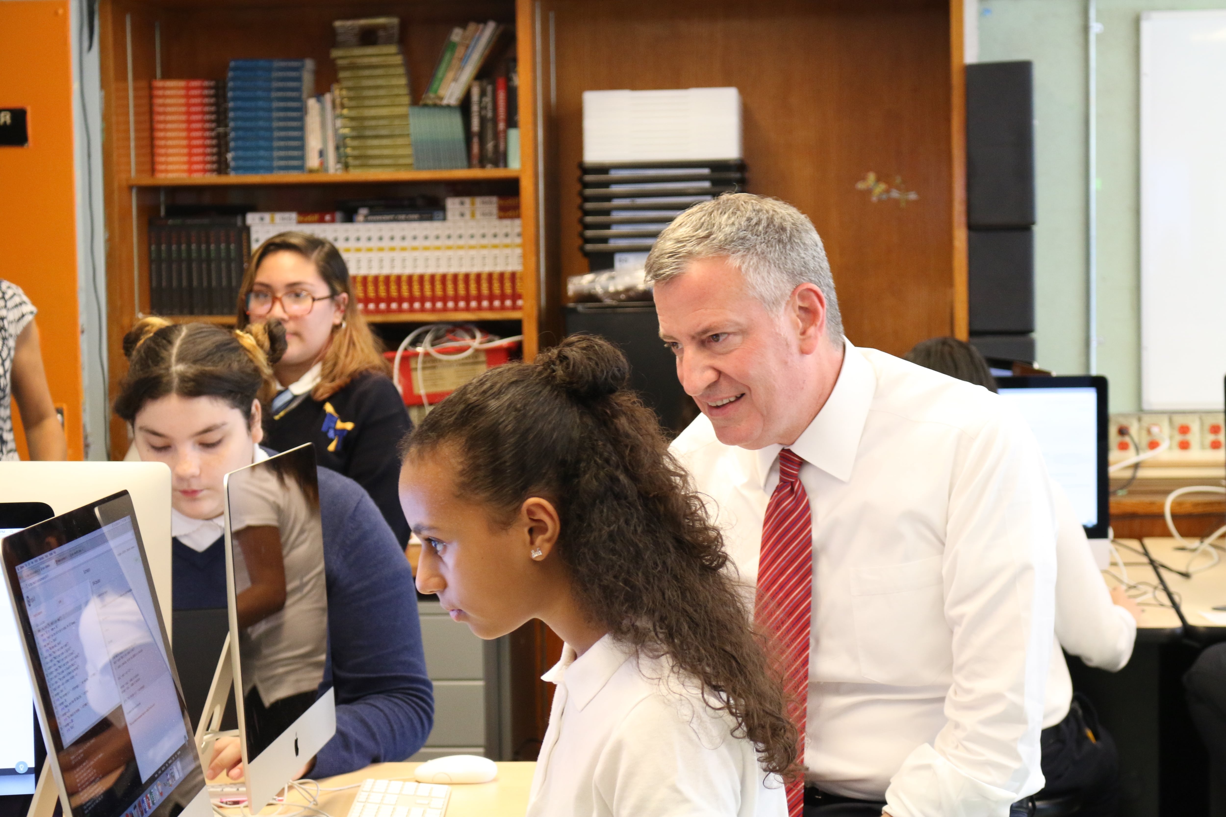 Mayor Bill de Blasio learns about computer science from a student at the Laboratory School of Finance and Technology in the Bronx