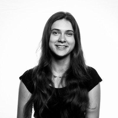 Black and white headshot of a young woman with long dark hair wearing a dark, short-sleeve t-shirt.