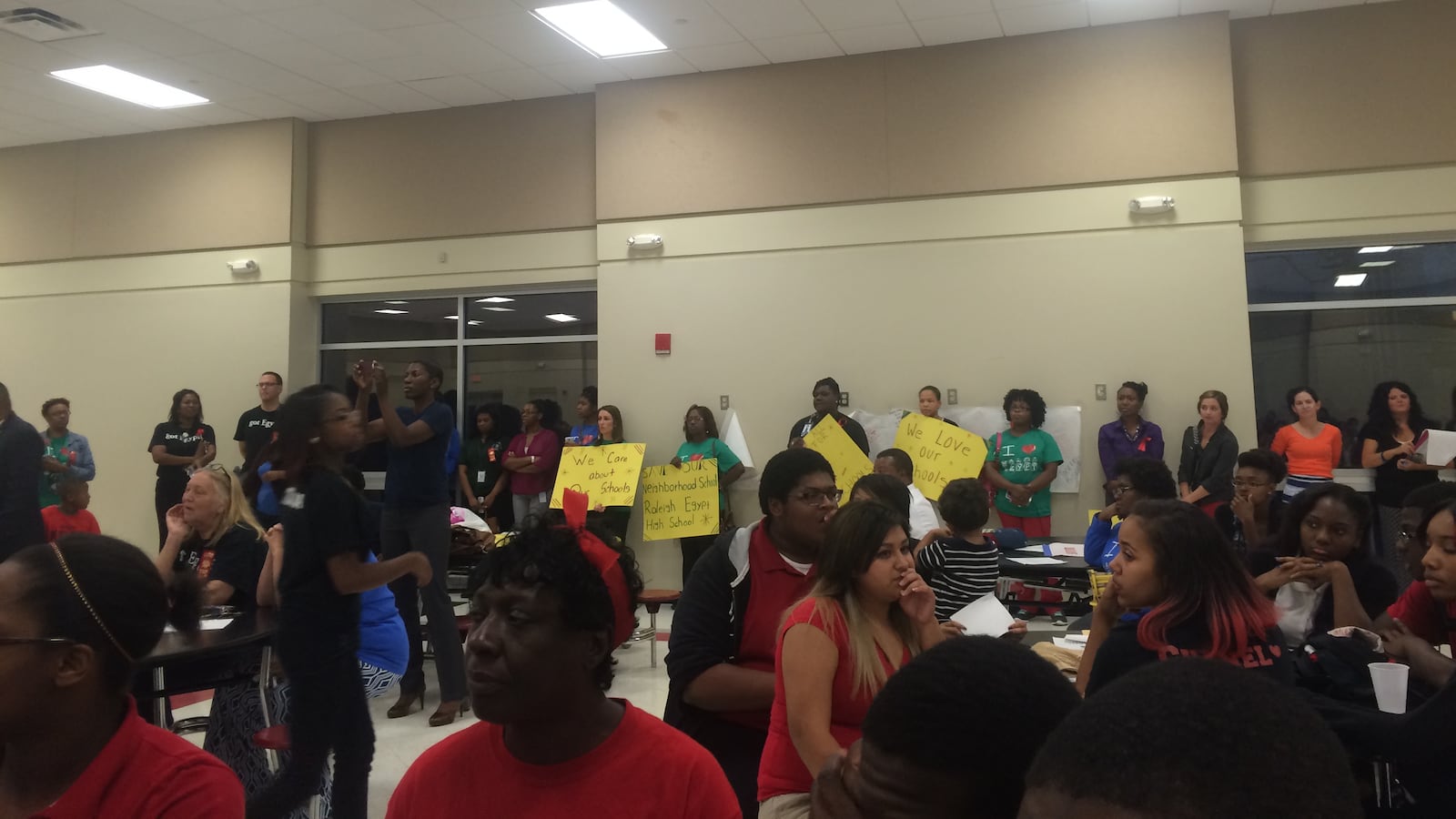 Teachers held signs protesting the ASD takeover during a community meeting at Denver Elementary