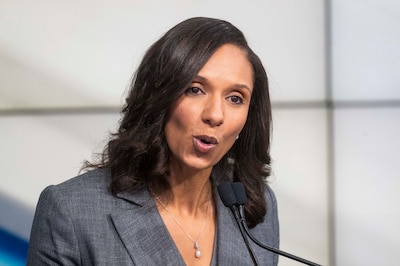 A photograph of a Black woman in a suit speaking in a debate.