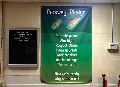 A green banner hangs on a wall.