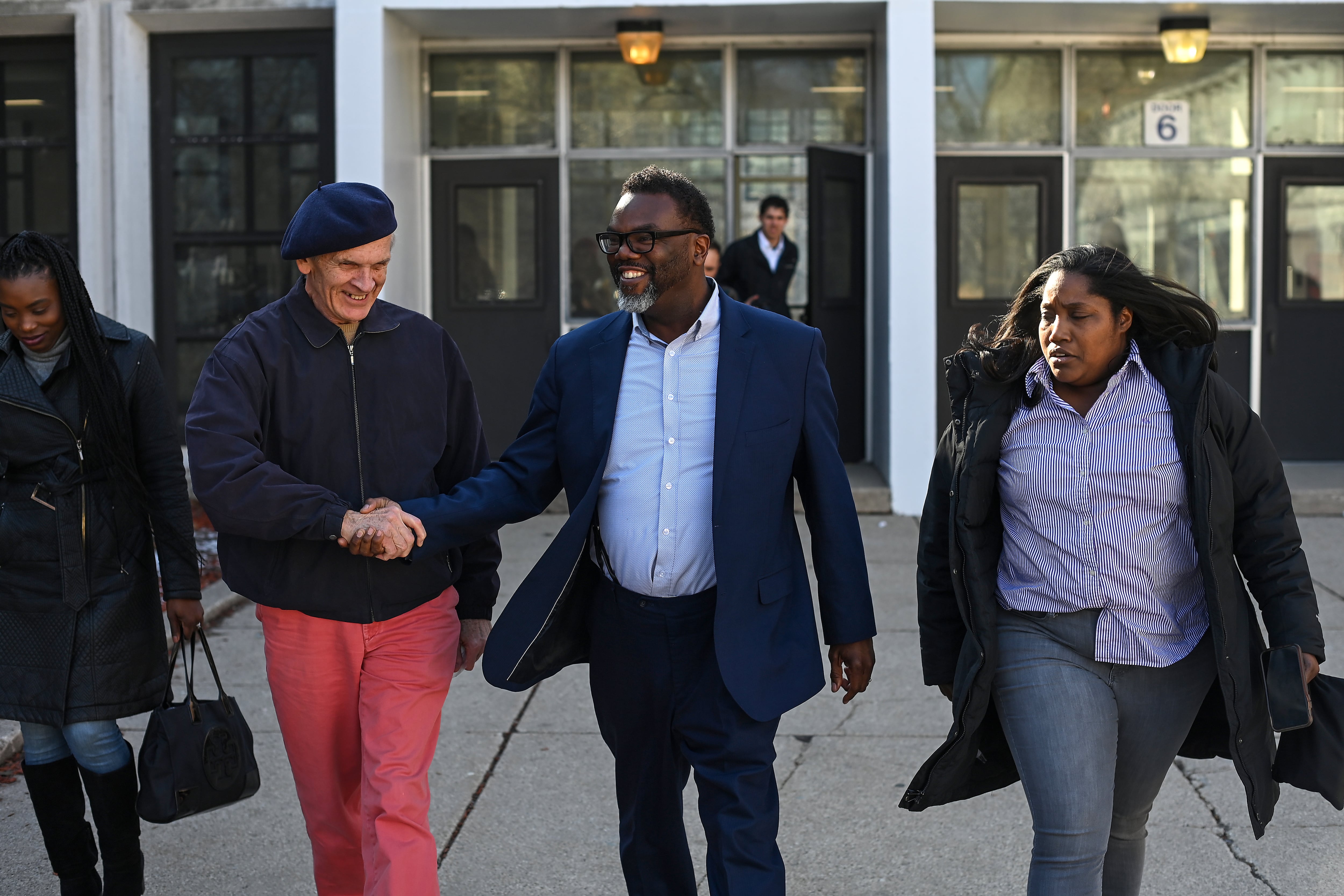 A group of four people including a man running for mayor walk out of a school building on Chicago’s South Side.