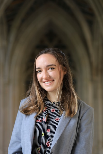 Headshot of a young woman wearing a gray blazer and patterned shirt.