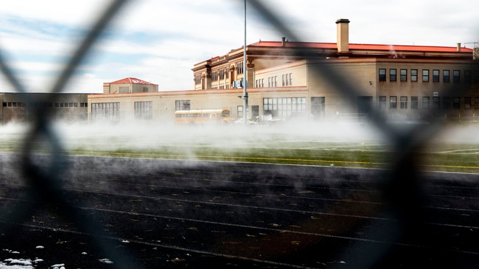 A high school as seen through a chain link fence.