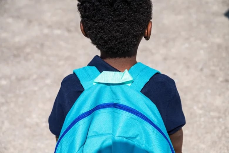 The back of a student who is wears a big blue backpack during a back-to-school event at Jackie Robinson Elementary School in Bronzeville.