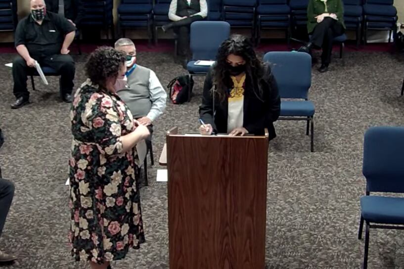 Janet Estrada signs paperwork at the podium as she is sworn in.