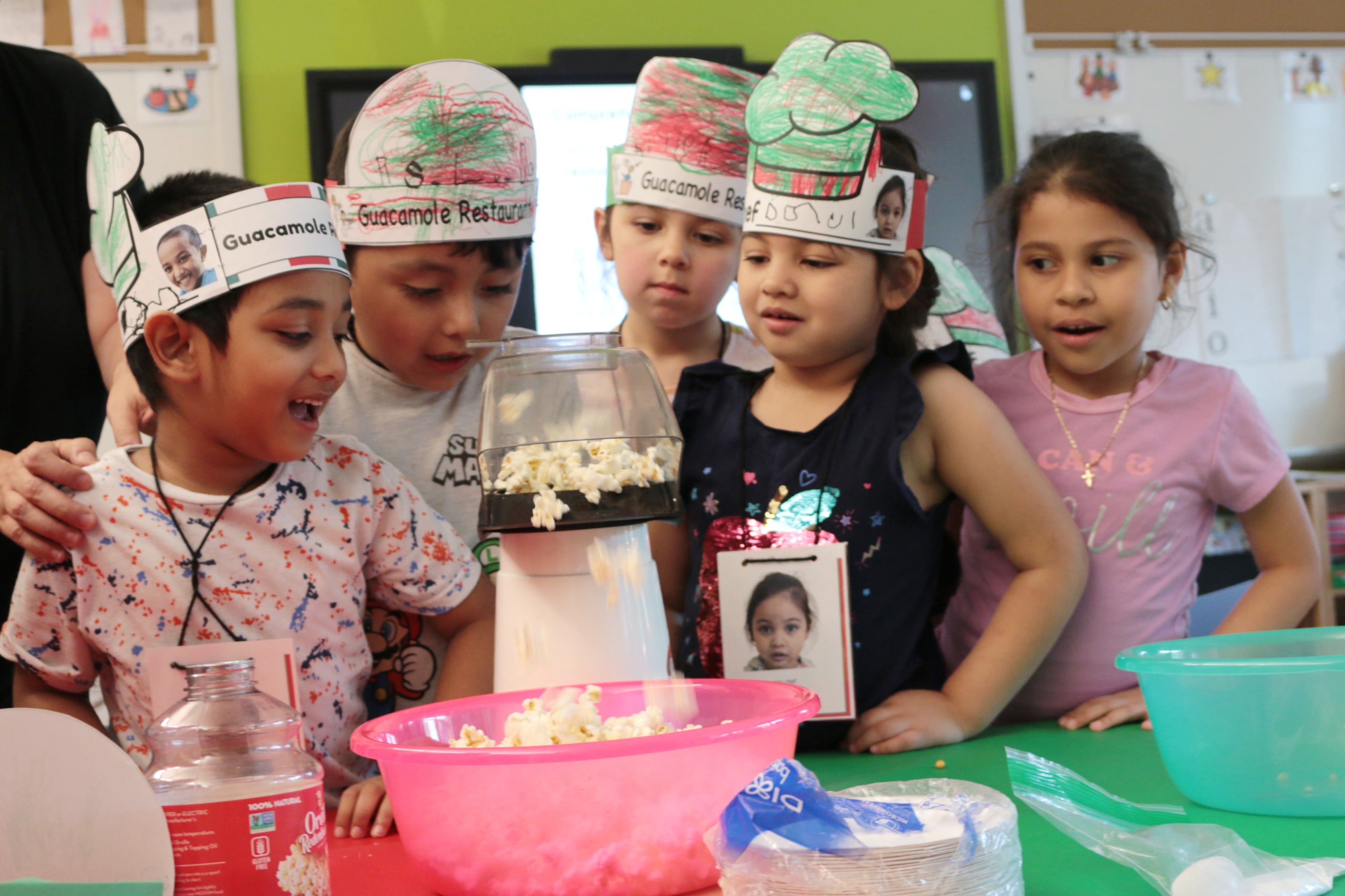 A group of five students watch as popcorn pops.