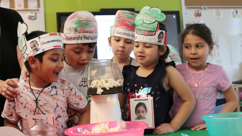 A group of five students watch as popcorn pops.