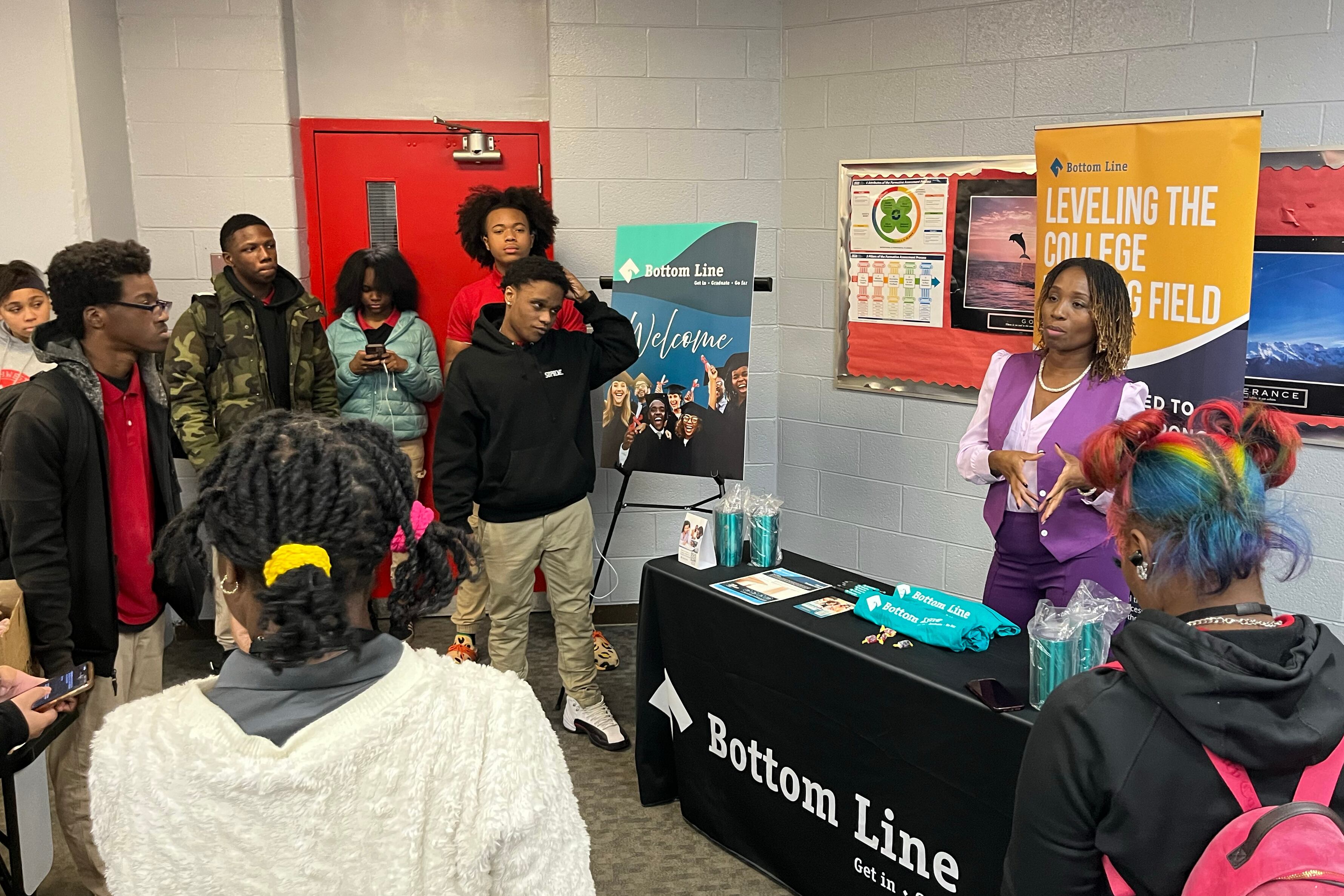 An adult speaks with a group of high school students.