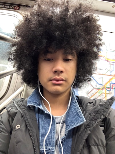 A teen with a t-shirt, jeans jacket and gray coat.