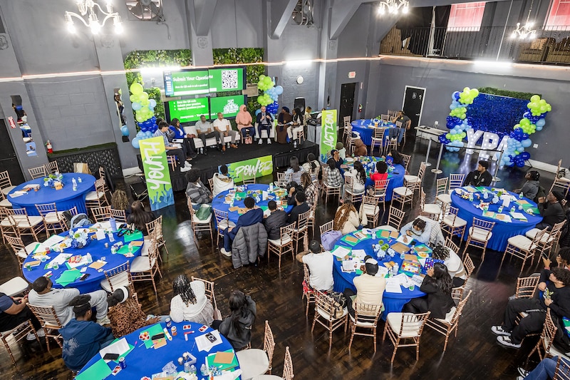 An aerial photograph of a large event room with tables and chairs full of people.