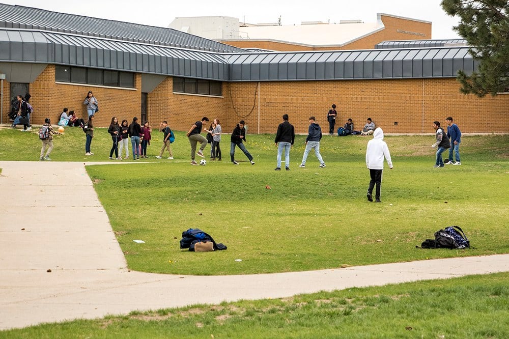 Students stand on the lawn of a high school.