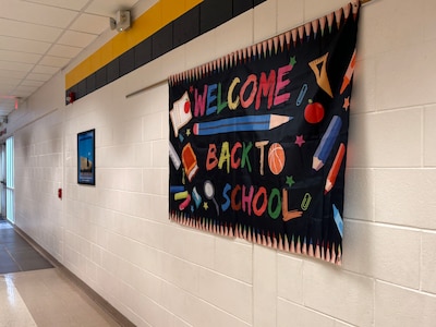 A photograph of a large sign on a school hallway wall that reads "Welcome back to school."