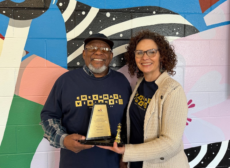 A photograph of two adults holding an award and smiling for a photograph.