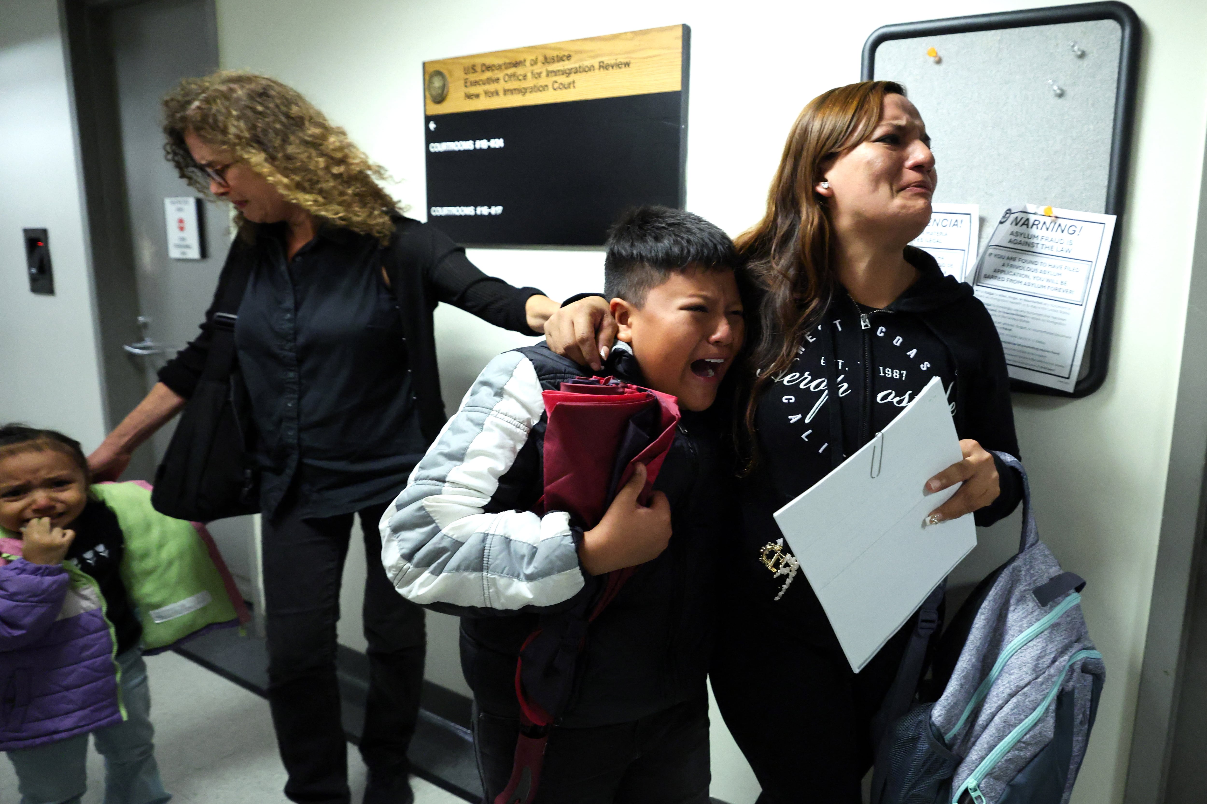 A woman in a black top holds onto a crying boy.